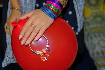 young girl holding her bracelet and red ballon