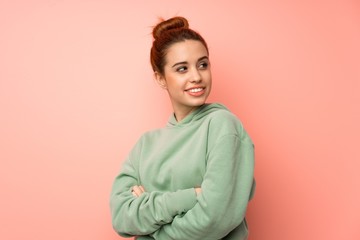 Young redhead woman with sweatshirt with arms crossed and happy