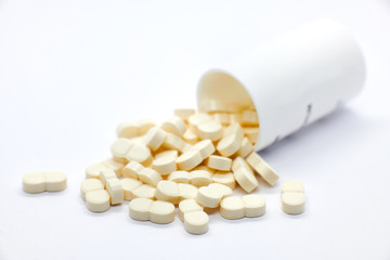 pills coming out of bottle on white background