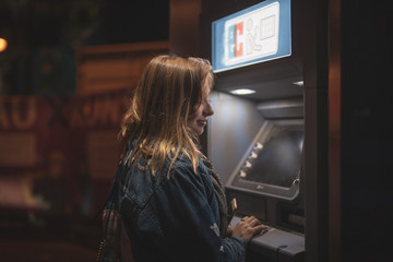 Fototapeta na wymiar Junge Frau alleine Nachts am EC Automaten