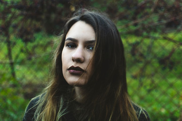 Movie-like portrait of a handsome pale-skinned brunette with blonde and brown strands. Stunning girl with deep black eyes looking at the camera. 