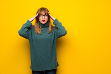 Woman with glasses over yellow wall unhappy and frustrated with something