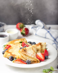 Thin pancakes with strawberries and blueberries, jam, condensed milk, delicious Breakfast. Russian traditional dessert for Shrovetide celebration (maslenitsa). French crepes - obrazy, fototapety, plakaty