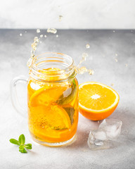 Cold tea with orange, mint and ice, sweet summer drink, refreshing lemonade, juicy cocktail. Spray, splash