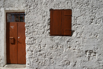 Fototapeta na wymiar Brown window on the white wall background in the old part of the city of Rhodes. Greece