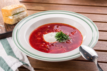 Red beetroot soup borshch with beef and sour cream on wooden table