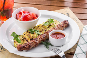 Shish kebab with grilled zucchini and fresh tomatoes on wooden table