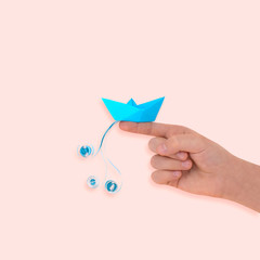 Girl holds paper boat with wave on her finger