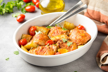 Baked chicken thighs (legs) with crispy crust, potatoes and cherry tomatoes. Simple delicious homemade dinner, traditional meal. Everyday food cooked in oven