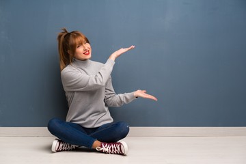 Redhead woman siting on the floor holding copyspace to insert an ad