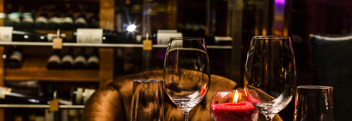 Two glasses of wine white and red standing on a table with candle in the sun light
