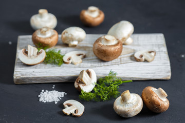 Composition with fresh champignon mushrooms on wooden board. Rustic style