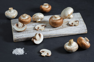 Composition with fresh champignon mushrooms on wooden board. Rustic style