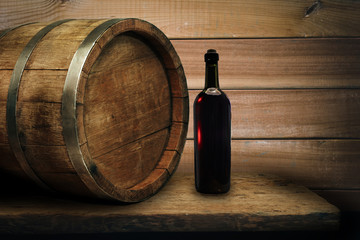 Red wine bottle on a old oak wooden table background barrel.