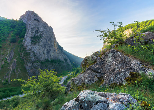 beautiful mountain landscape of romania. huge rocky formations on top of a hill. road winding down the valley. wonderful springtime scenery at sunrise