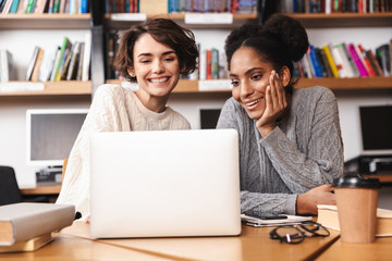 Two cheerful young girls students studying