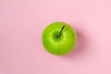 Fresh and green apples on a pink color background.