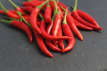 A lot of sharp hot spice red chilli cayenne pepper with wet drops of freshness water dew on a black...