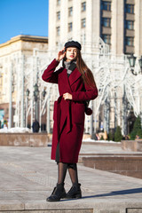 Fototapeta premium Beautiful girl in stylish in a long burgundy coat