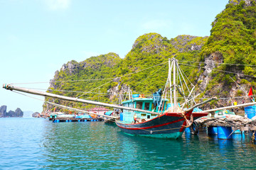 Halong Bay, Vietnam. Small Wooden Fishing boats docked at Floating Fishing village with Vietnam National Flag © birdiegal