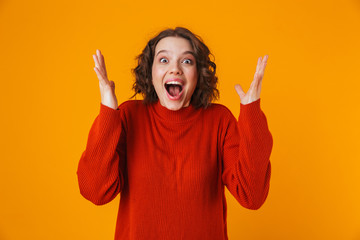 Excited emotional happy young pretty woman posing isolated over yellow wall background.