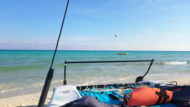 Boat Overlooking The Ocean Sitting On The Beach With Parasailers And Floats On The Horizon During The Day In Mexico