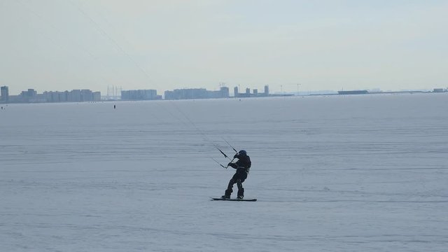 a snowboarder with a parachute rides around the bay in the city of St. Petersburg