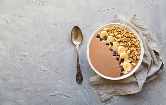 Chocolate smoothie bowl with bananas, granola and peanuts