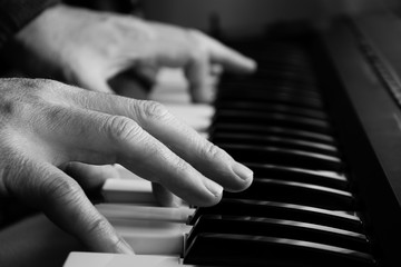 Close up on man's hands playing piano in Black and White.