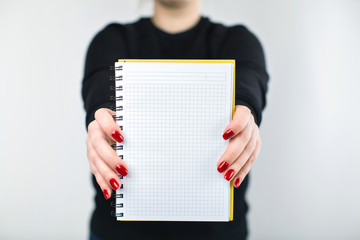 girl in a black sweater and red nails holding a notebook