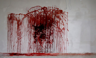 Large splatter of blood on a dirty grey wall and on the floor, murder scene in abandoned building
