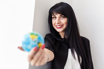 Young Beautiful smiling brunette woman dressed in a black business suit holding a globe of the planet Earth.