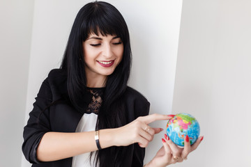 Young Beautiful smiling brunette woman dressed in a black business suit holding a globe of the planet Earth.