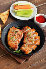 Baked pork steaks in frying pan, tomato sauce and fresh celery