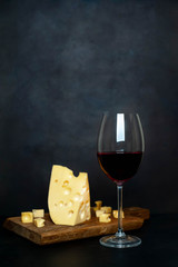 wine and delicious cheese on a cutting board, background stone