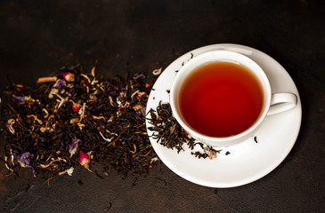 tasty tea in a white mug, scattered tea on a stone background