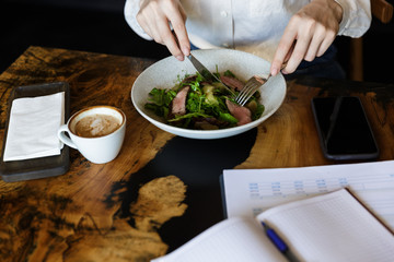 Close up of a woman eating salad while sitting at the cafe