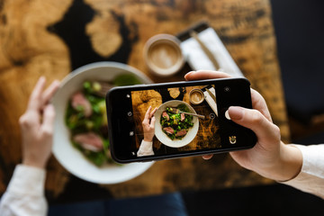 Woman taking a picture of her lunch - obrazy, fototapety, plakaty