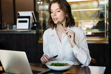 Smiling businesswoman having lucnch at the cafe indoors