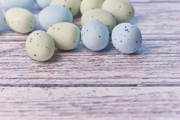 yellow and blue dragee eggs on a white wooden background, macro color photo