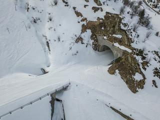 Aerial view of tunnel with snow covered road in winter landscape in Swiss mountains.