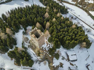 Aerial view of medieval tower ruins of fortess in forest. Stone tower on peak in Swiss alps with...