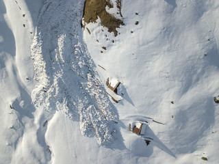 Aerial view of snow avalanche on mountain slope. Wet snow in spring sliding downhill.