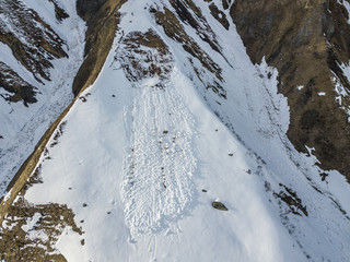 Aerial view of snow avalanche on mountain slope. Wet snow in spring sliding downhill.