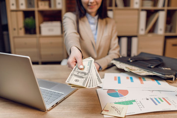 Hand giving money.  Businesswoman in eyeglasses holding dollar currency.
