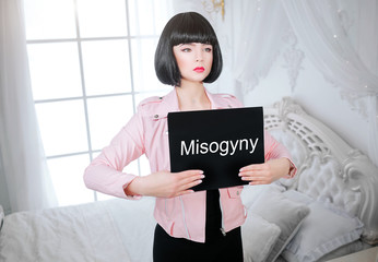 Fashion freak. Glamour synthetic girl, fake doll with empty look and short black hair is holding...