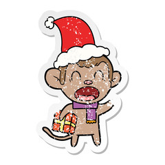 shouting distressed sticker cartoon of a monkey carrying christmas gift wearing santa hat