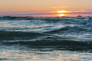 Fototapeta premium Sunset over the sea. Reflection of sunlight in the sea waves. Red and yellow sky in the rays of the sunset.