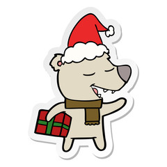 sticker cartoon of a bear with present wearing santa hat