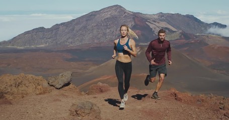 Trail running in the mountains, young athletic man and woman working out in the outdoors, running adventure lifestyle